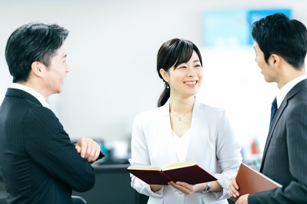 会議テーブルを囲み意見交換するビジネスパーソン３名の写真